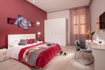 a bedroom with a bed with red walls and a desk at Well Done Montebello in Rome