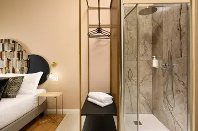 a shower with a glass door next to a bed at Velantia Vaticano - Guesthouse in Rome