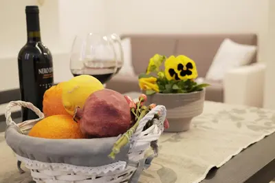 a basket of fruit on a table with a glass of wine at Pisetzky-Spadaro Apartments - Vegezio Roma in Rome