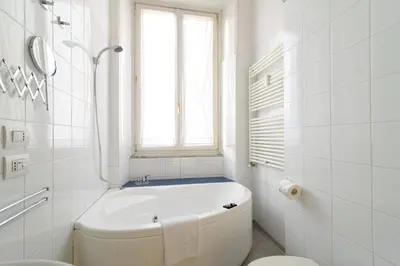 a white bathroom with a tub and a window at White Napoleone Apartment in Rome
