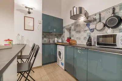 a kitchen with blue cabinets and a washer and dryer at GuestHost - Monti Artistic Flat in Rome