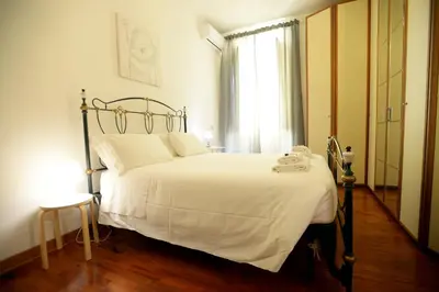 a bedroom with a bed with white sheets and a window at MECENATE DELUXE COLOSSEUM in Rome