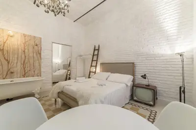 a white bedroom with a bed and a tv at Romantic Vintage Colosseum Suite in Rome