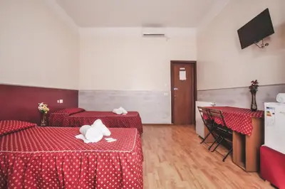 a room with two beds and two tables and a television at Vertex Guest House in Rome