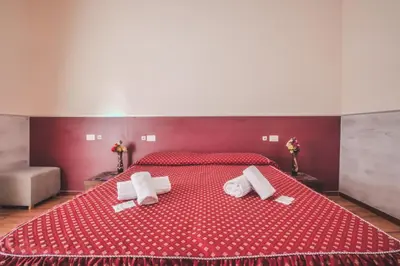 a red bed with two towels on top of it at Vertex Guest House in Rome
