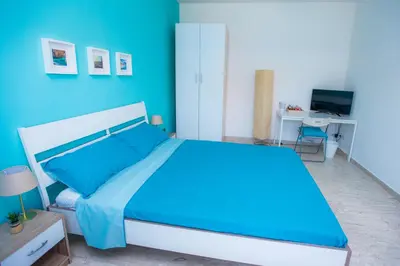 a blue bedroom with a large bed and a desk at Quelli della via Gluck in Rome