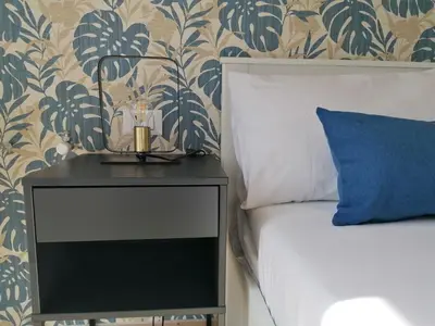 a nightstand next to a bed with a blue pillow at Appia Garden in Rome