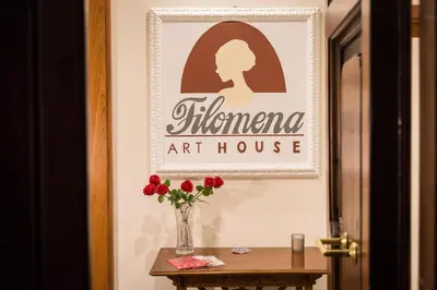 a vase of red flowers on a table with a sign at Filomena Arthouse in Rome