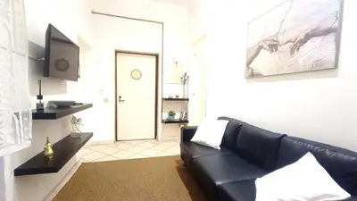 a living room with a black leather couch and a door at Lovely 5 min walk to Saint Peter Basilica in Rome