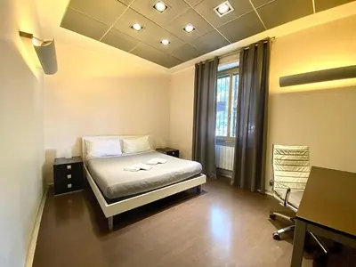 a bedroom with a bed and a desk and a window at Gemini Guest House in Rome