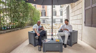 two men sitting in chairs under an umbrella at Relais central Turati in Rome