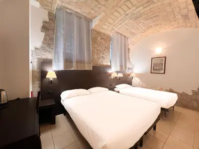 two beds in a room with a stone wall at Saint Peter Loft in Rome