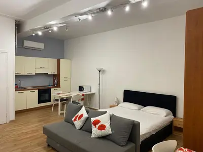 a bedroom with a bed and a couch and a kitchen at New studio a Trastevere in Rome