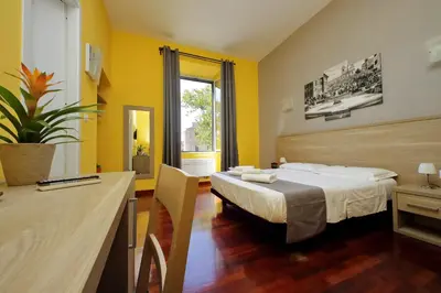 a hotel room with a bed and a desk at Porta Pia Comfy Rooms in Rome