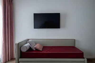 a couch with two pillows and a tv on a wall at Palazzo Lupardi Relais in Rome