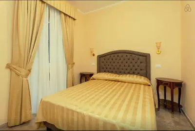 a bedroom with a bed with two tables and a window at VIA VENETO SUITE 107 in Rome