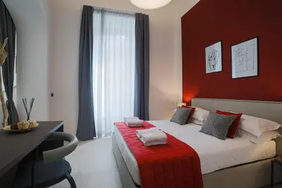 a bedroom with a bed with a red wall at Bespoke Roma Suites in Rome