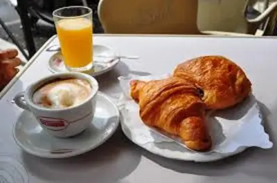 a tray with a coffee and a croissant and a cup of orange juice at Luxy Vatican Apartment in Rome