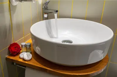 a white sink on a wooden shelf in a bathroom at Tula Inn in Rome