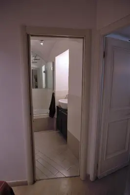 a bathroom with a door leading to a tub and a sink at Grotte Flat in Rome