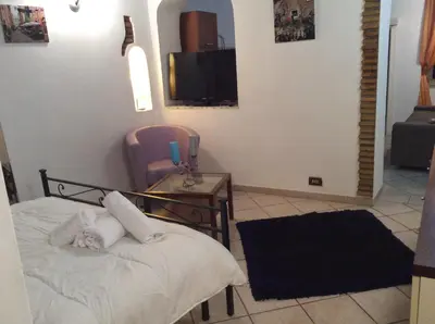 a bedroom with a bed and a chair and a television at JUSTACASA alla SCALA Trastevere in Rome