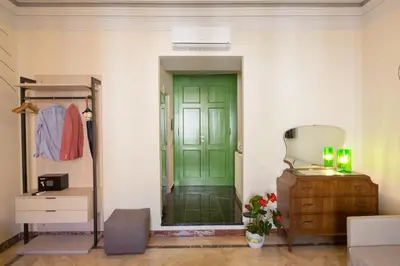 a green door in a white room with a dresser at Tritone 125 Suite in Rome