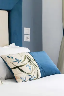 a bed with a blue and white pillow on it at GHR Navona Inn in Rome
