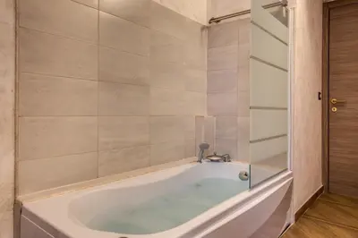 a bath tub with a glass door in a bathroom at AMICI GUESTHOUSE in Rome