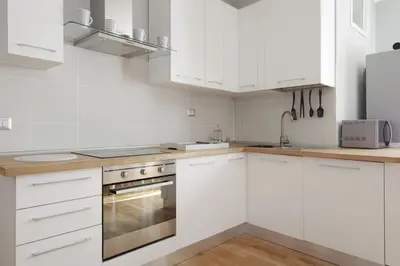 a white kitchen with white cabinets and stainless steel appliances at San Peter Apartment - your home in the heart of Rome in Rome