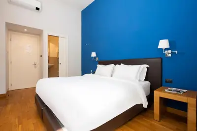 a large white bed in a room with a blue wall at Sky Blue Place Rome in Rome