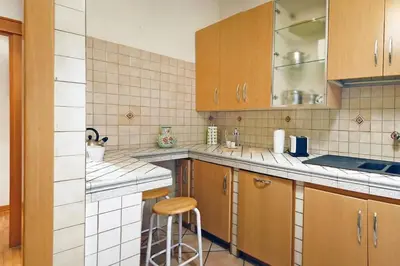 a kitchen with wooden cabinets and a stool in it at Elegant Apartment Via Veneto by Varental in Rome