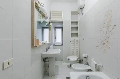 a white bathroom with two sinks and a toilet at Elegant Apartment Via Veneto by Varental in Rome