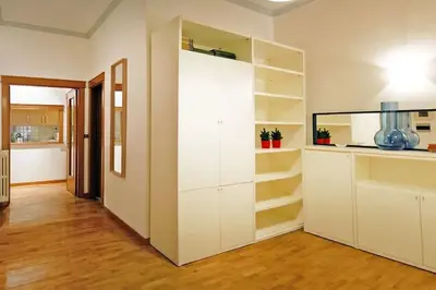 a white kitchen with white cabinets and wooden floors at Elegant Apartment Via Veneto by Varental in Rome