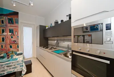 a kitchen with white cabinets and a stove top oven at San Pietro Moonlight Luxury Apartment in Rome