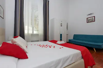 a white bed with red pillows and a blue couch at Sanctuary Home in Rome
