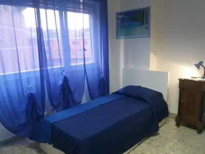 a bedroom with a blue bed in front of a window at Apartament Silvy Trastevere in Rome