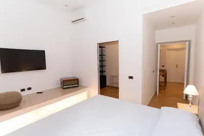 a white bedroom with a bed and a tv on the wall at Luxury Laura Vatican Apartment ROMA CENTRO in Rome