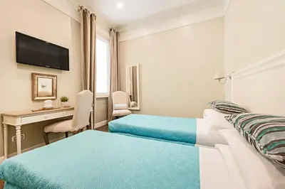 a hotel room with two beds and a desk at Le Stanze Di Elle in Rome