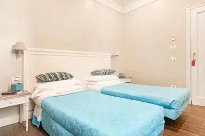 two beds in a white room with blue sheets at Le Stanze Di Elle in Rome