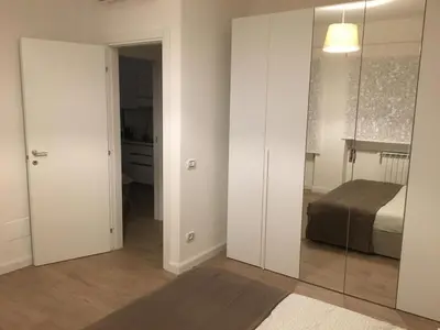 a bedroom with white walls and a bed and a mirror at GLI ARANCI Apartment in Rome