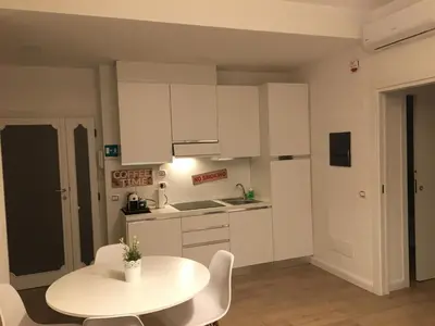 a white kitchen with a white table and chairs at GLI ARANCI Apartment in Rome