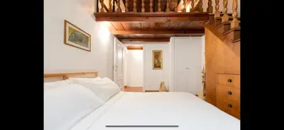 a bedroom with a white bed and a wooden staircase at IN FRONT OF COLISEUM 2 in Rome