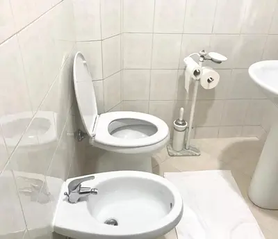 a white bathroom with a toilet and a sink at COLOSSEUM LUXURY ROOM in Rome