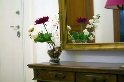 a vase of flowers on a table in front of a mirror at Il Melograno Holiday House in Rome