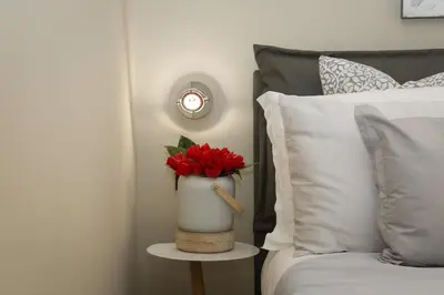 a vase with red flowers on a table next to a bed at 126 Gracchi Suites in Rome