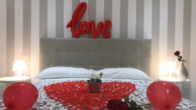 a bed with red balloons and a table with a love heart at San Pietro Dreaming Rooms in Rome