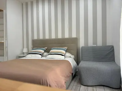 a bed and a chair in a bedroom with striped walls at San Pietro Dreaming Rooms in Rome
