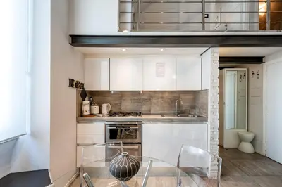 a kitchen with white cabinets and a glass table at Modern Loft Walk to St Peter IREX Apartment in Rome