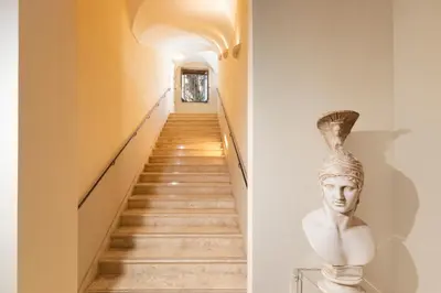 a staircase leading up to a hallway with a statue on the wall at Palm Suites - Small Luxury Hotels of the World in Rome