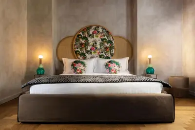 a bedroom with a large bed with a floral headboard at Palm Suites - Small Luxury Hotels of the World in Rome